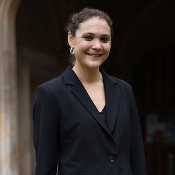 A woman in a black jacket outside an old stone building